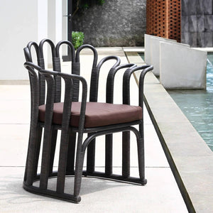 Black outdoor dining chair with maroon cushion. made from curved corolla, aluminum and synthetic rattan.